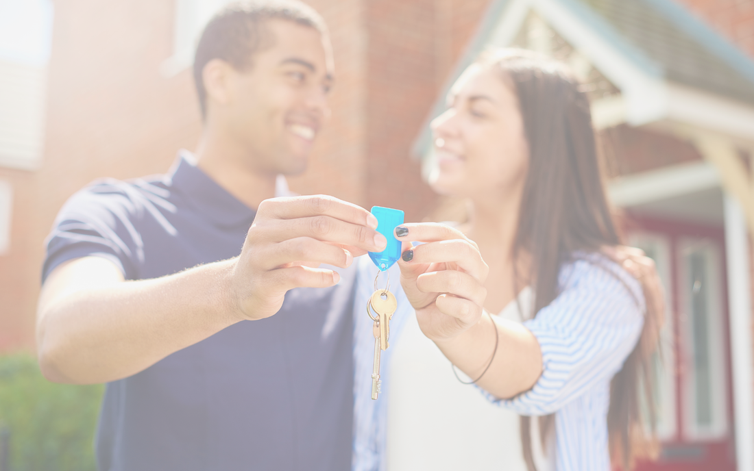 Couple standing outside new home with set of keys